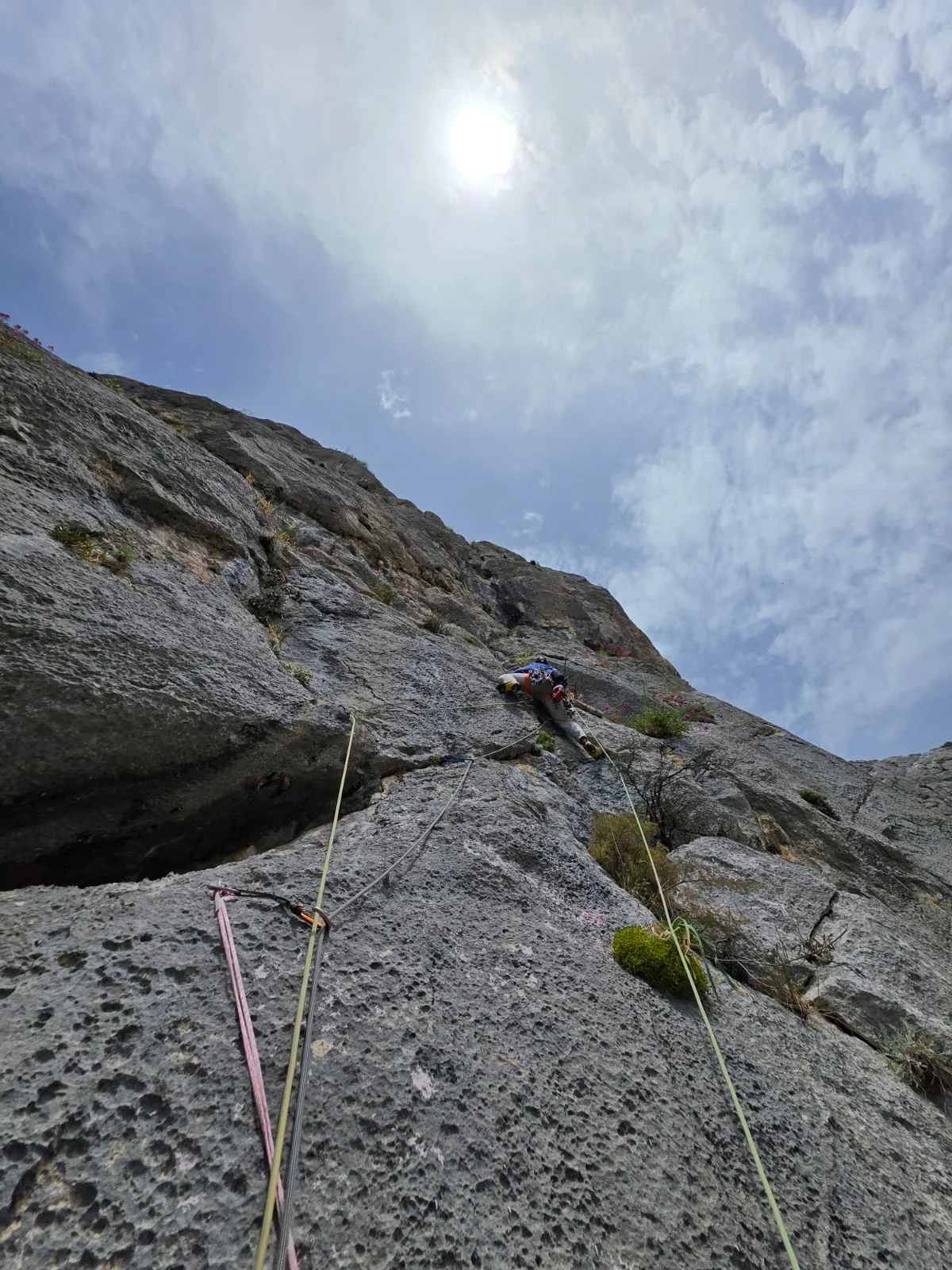 Kalkfelswand der Route Captain Blue mit Kletterseilen unter bewölktem Himmel.