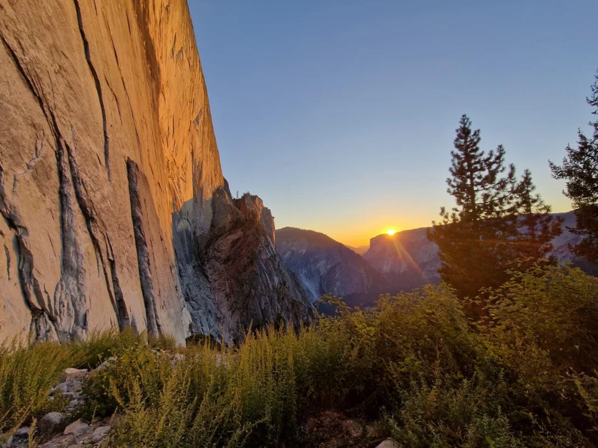 Sonnenuntergang am Wandfuß des Half Dome mit Granitwand und Bäumen.