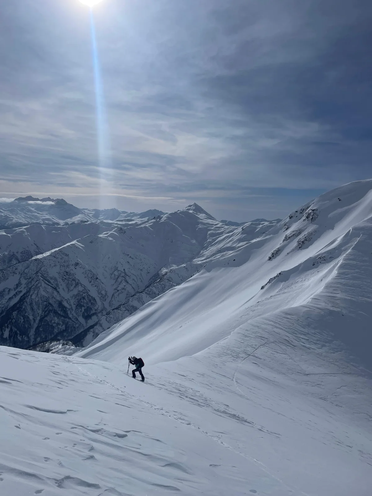 Skitourengeher in einem weiten Schneehang über den Bergen Swanetiens in Georgien.