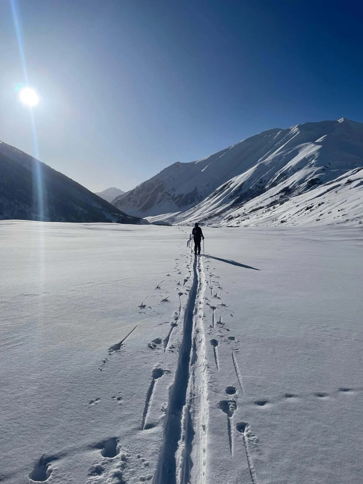 Skitourengeher auf einer langen Spur durch ein verschneites Tal im Großen Kaukasus.