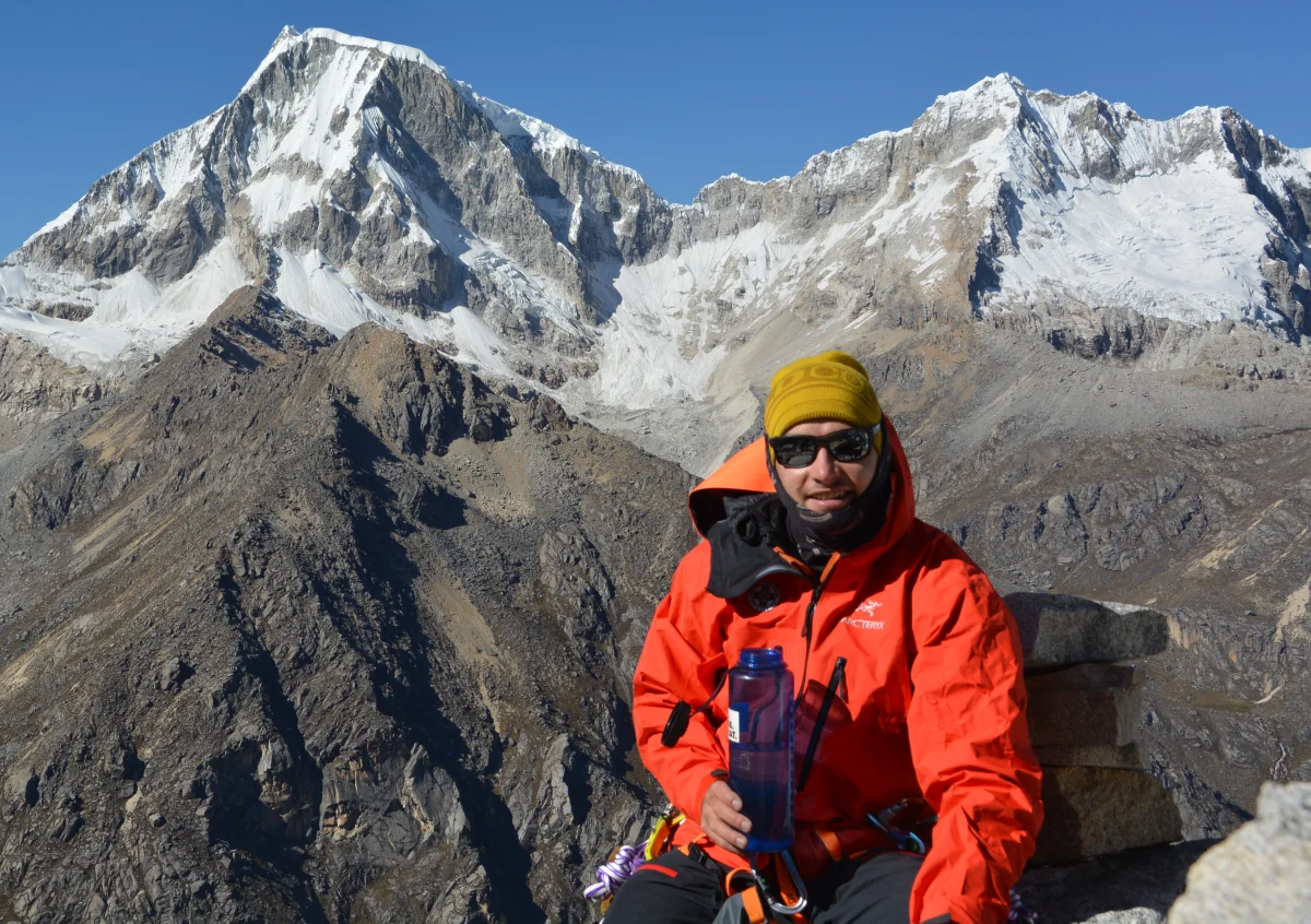 Ludwig Sandhacker in roter Bergjacke vor vergletscherten Gipfeln.