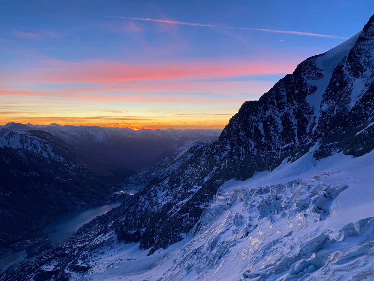 Snow-covered mountainside in colourful evening light.