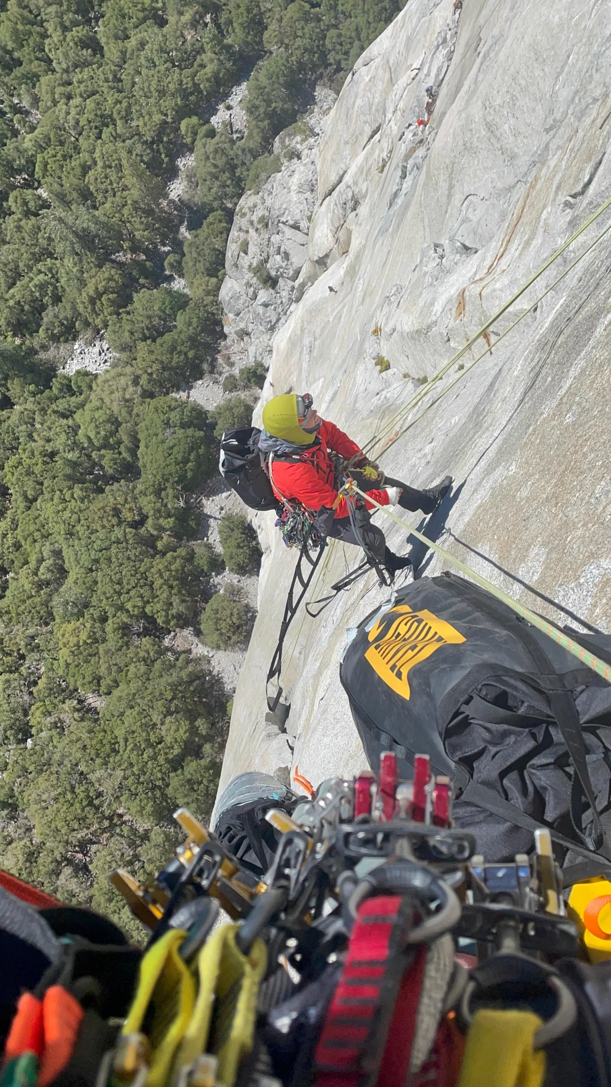 Climber with extensive equipment on a steep rock wall.
