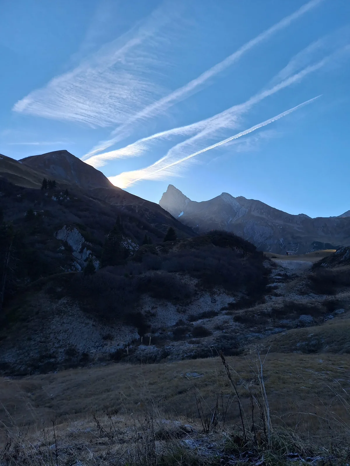 View across a mountain valley and rocky peaks beneath a blue sky.