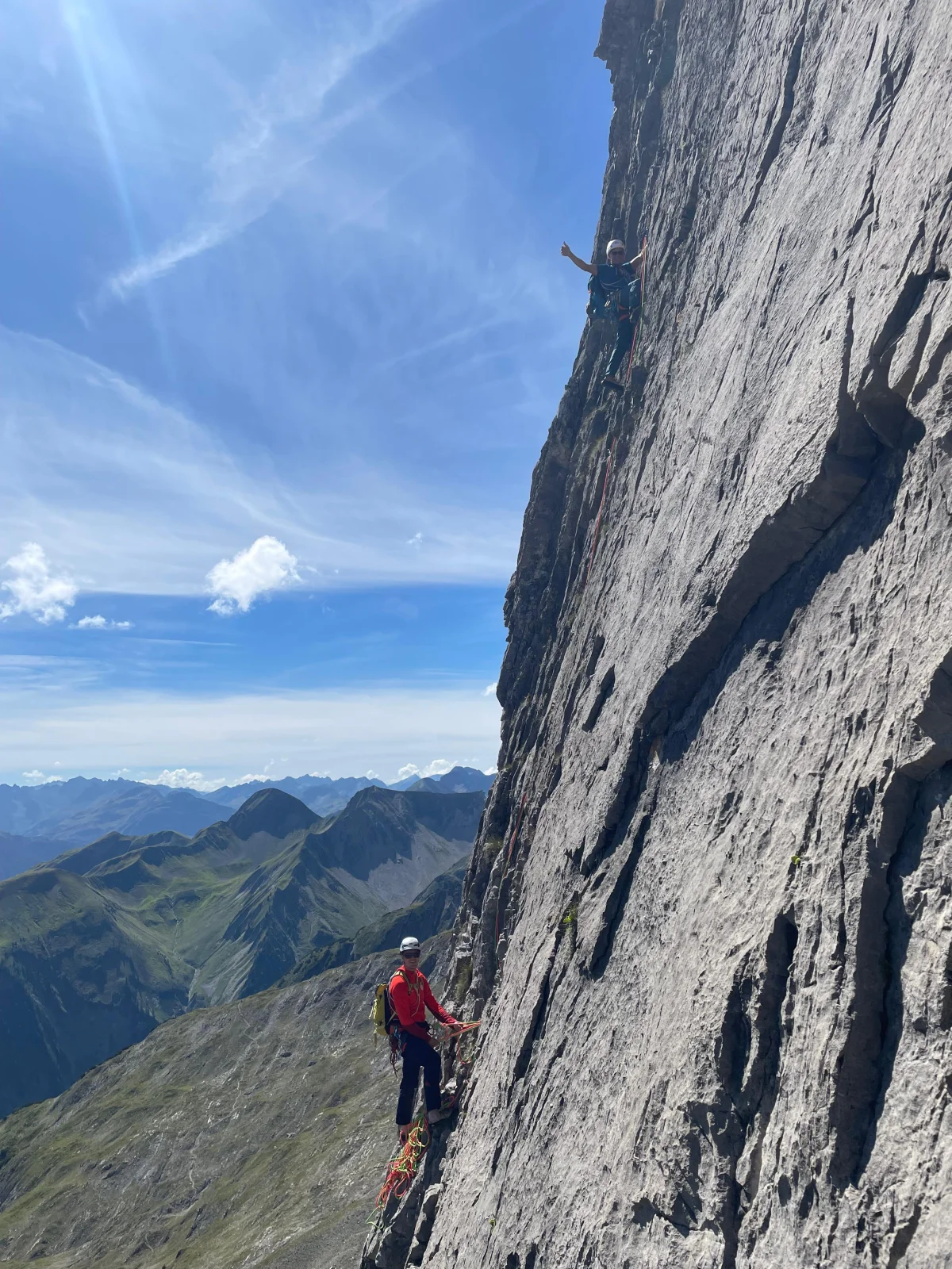 Roped climbers on a sunlit limestone wall.