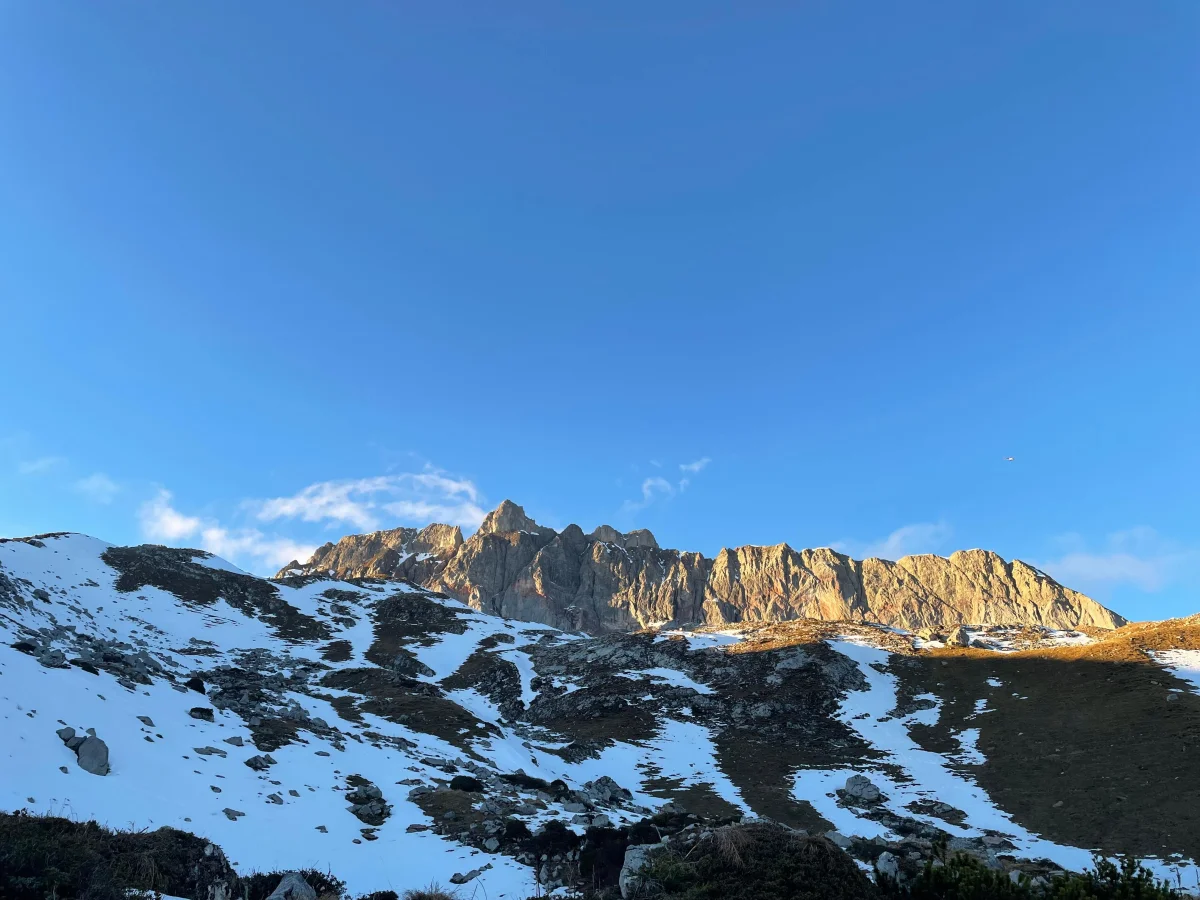 Sunlit rock wall above snow-covered slopes in the climbing area at Arlberg and in the Lechquellen Mountains.