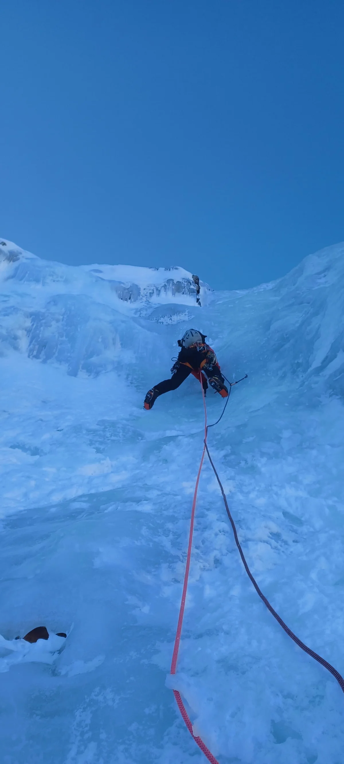 Anfängerfreundliche Eisklettertour in den Dolomiten: Eiskletterer mit Sicherungsseil an einem Eisfall.