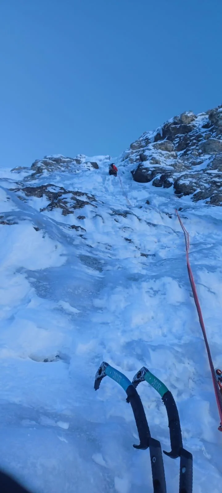 Beginner-Friendly Ice Climbing Tour in the Dolomites: Ice tools in front of a steep ice slope and blue sky.
