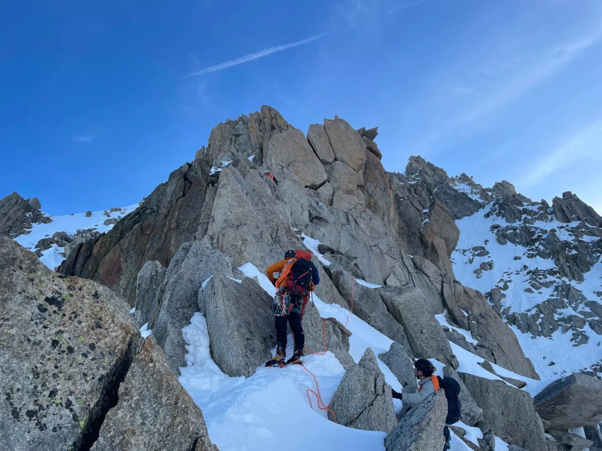 Arête de la Table on Aiguille du Tour: Roped climbers ascending granite boulders and snow.