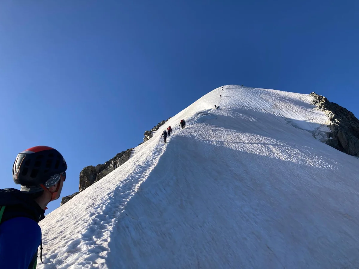 Biancograt on Piz Bernina: Mountaineer in front of a narrow snow ridge.