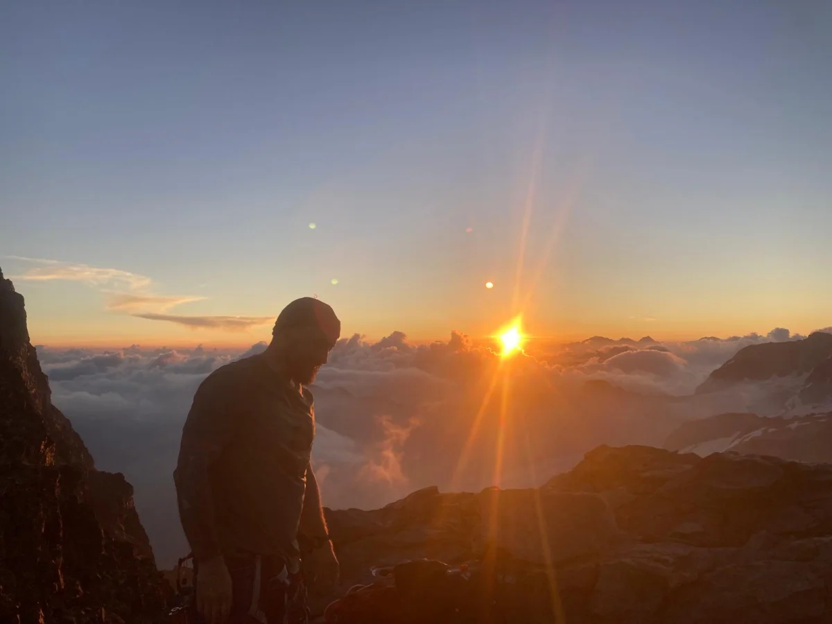 Biancograt on Piz Bernina: Mountaineer beside the rising sun above the mountains.