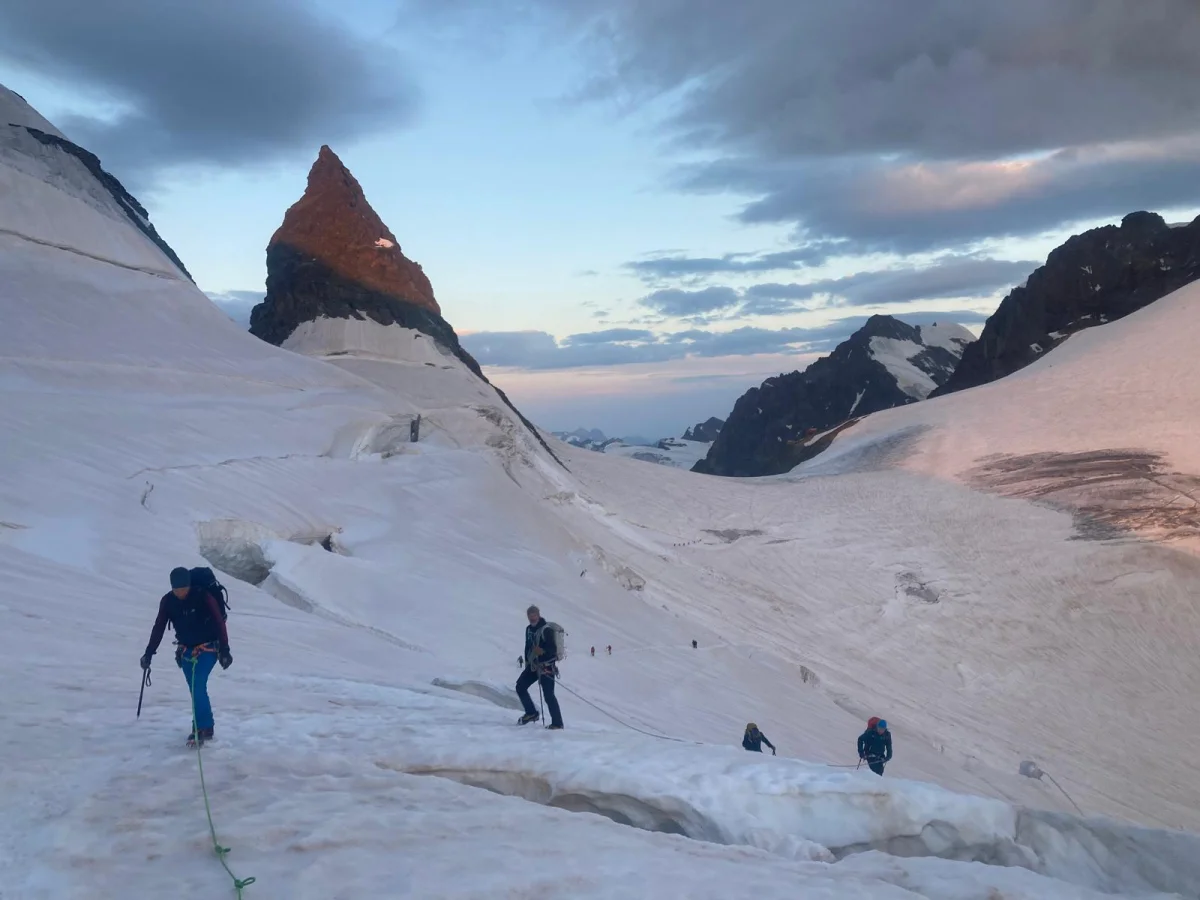 Biancograt on Piz Bernina: Roped mountaineers ascending a snow-covered glacier.