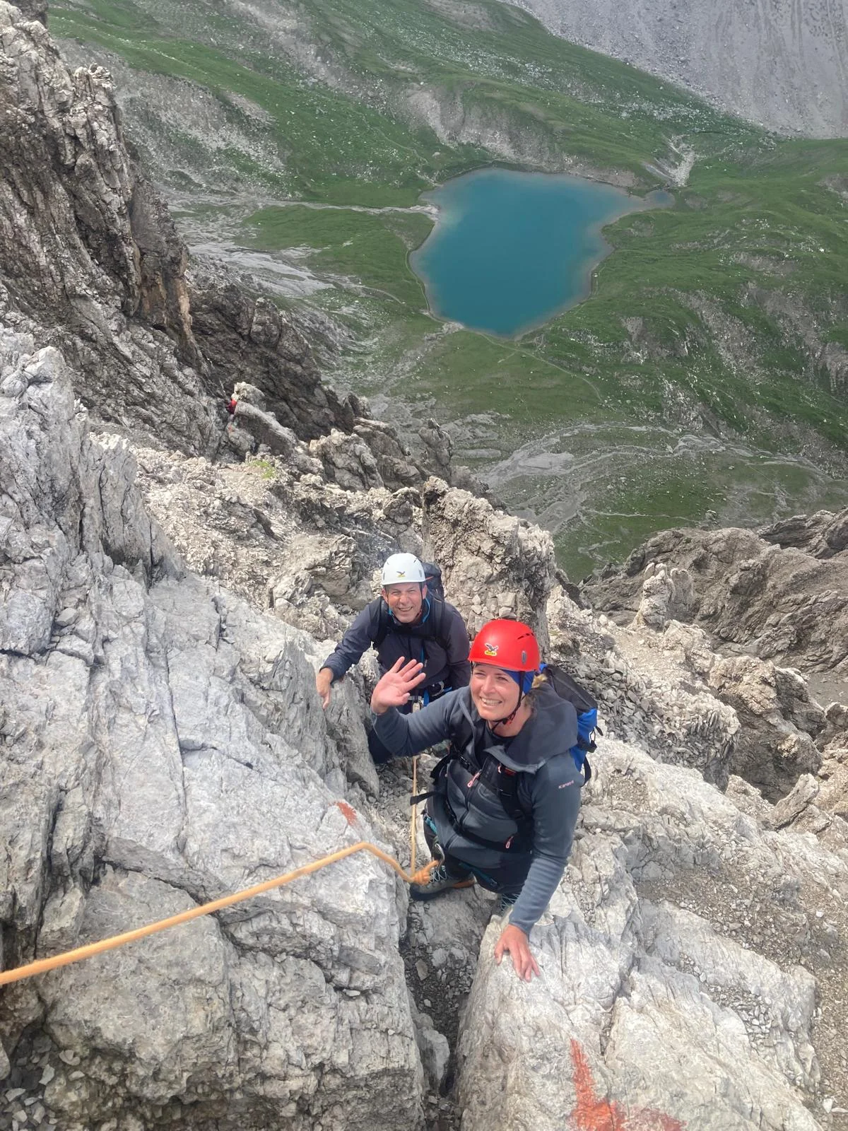 Dremelspitze – einer der schönsten Berge des Lechtals: Zwei lachende Kletterer am Seil mit Bergsee im Hintergrund.