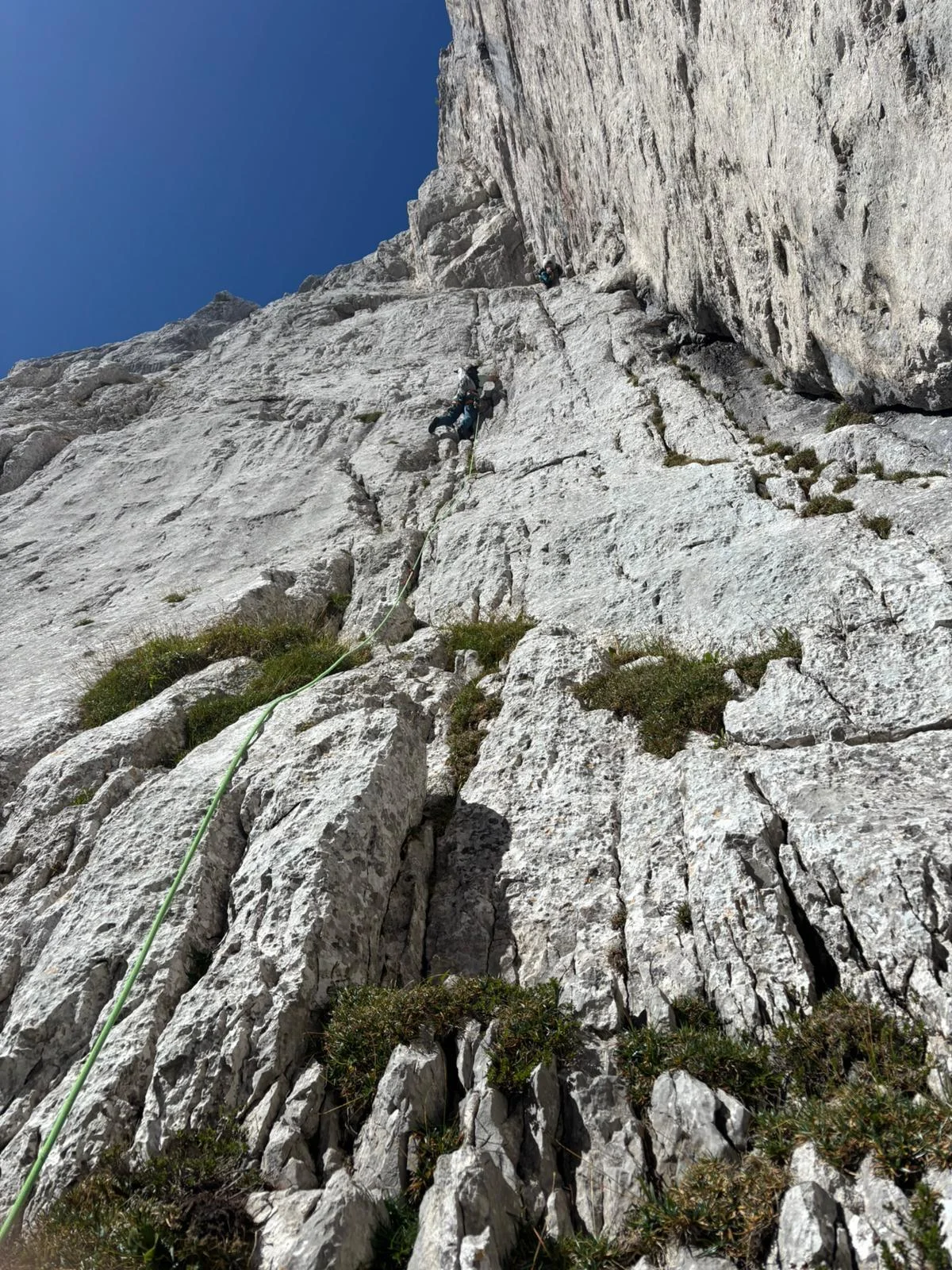Fleischbank East Face – Dülfer Route: Roped climbers with a green rope on a grey rock wall.