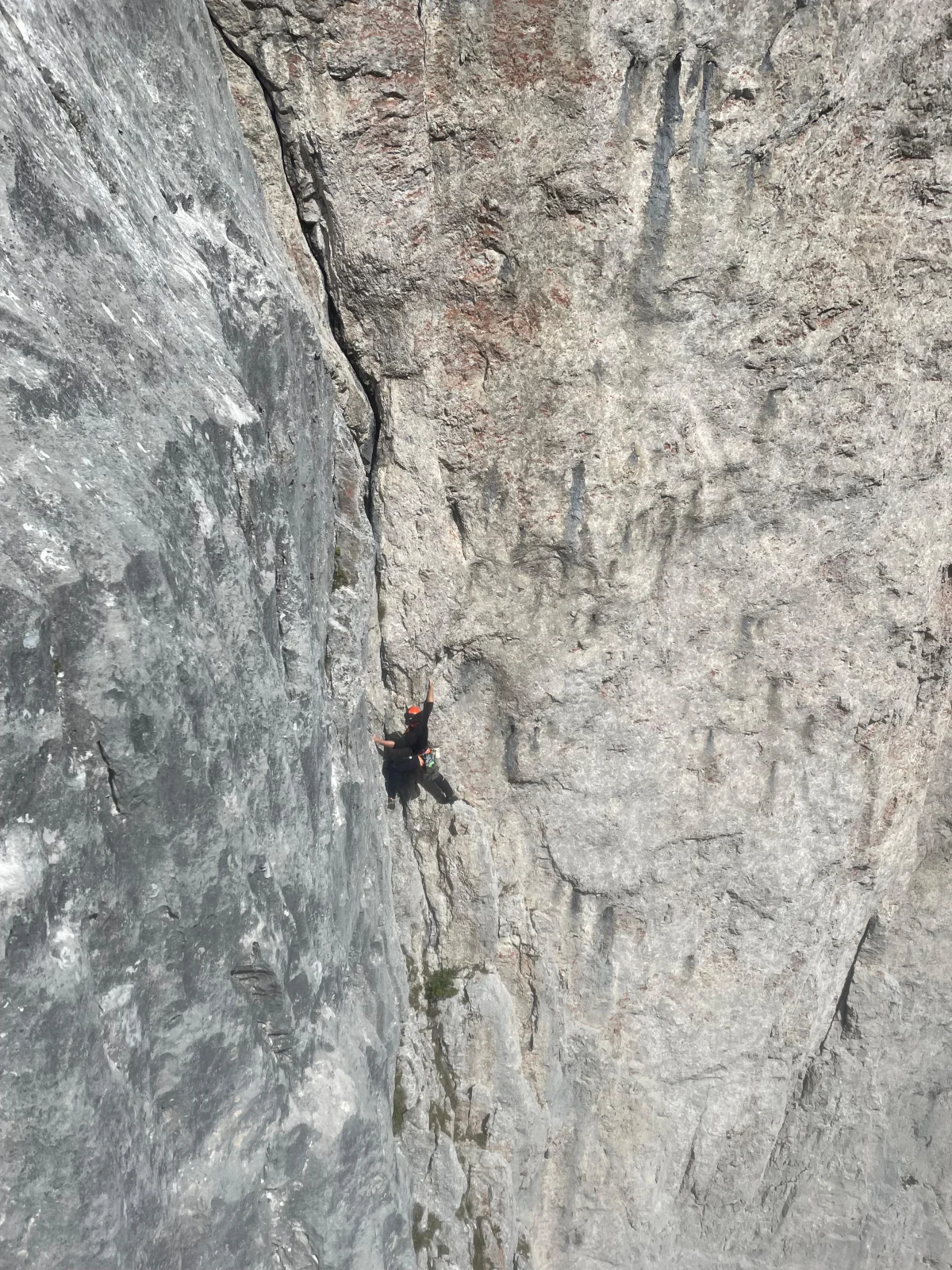 Fleischbank East Face – Dülfer Route: Climber wearing a red helmet on a vertical wall.