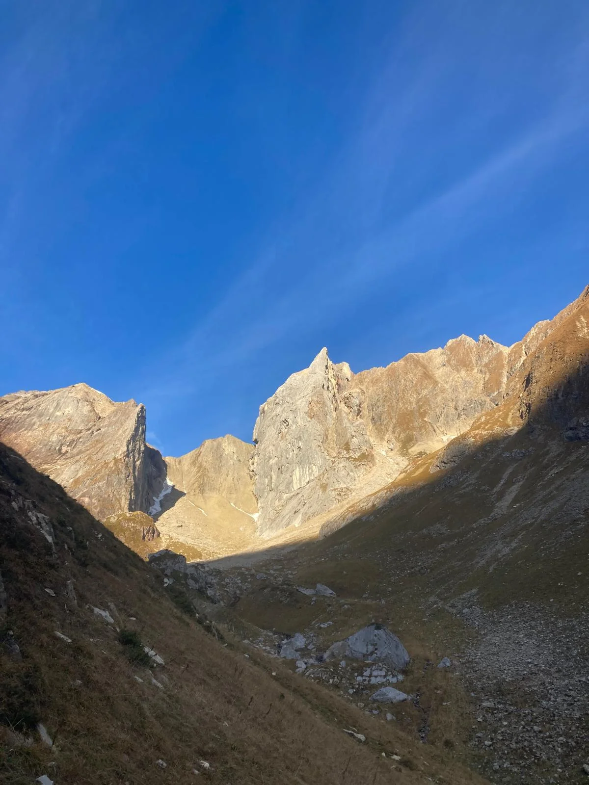 Freispitz South Face – Schreck Heel: Sunlit rock wall above a mountain valley.