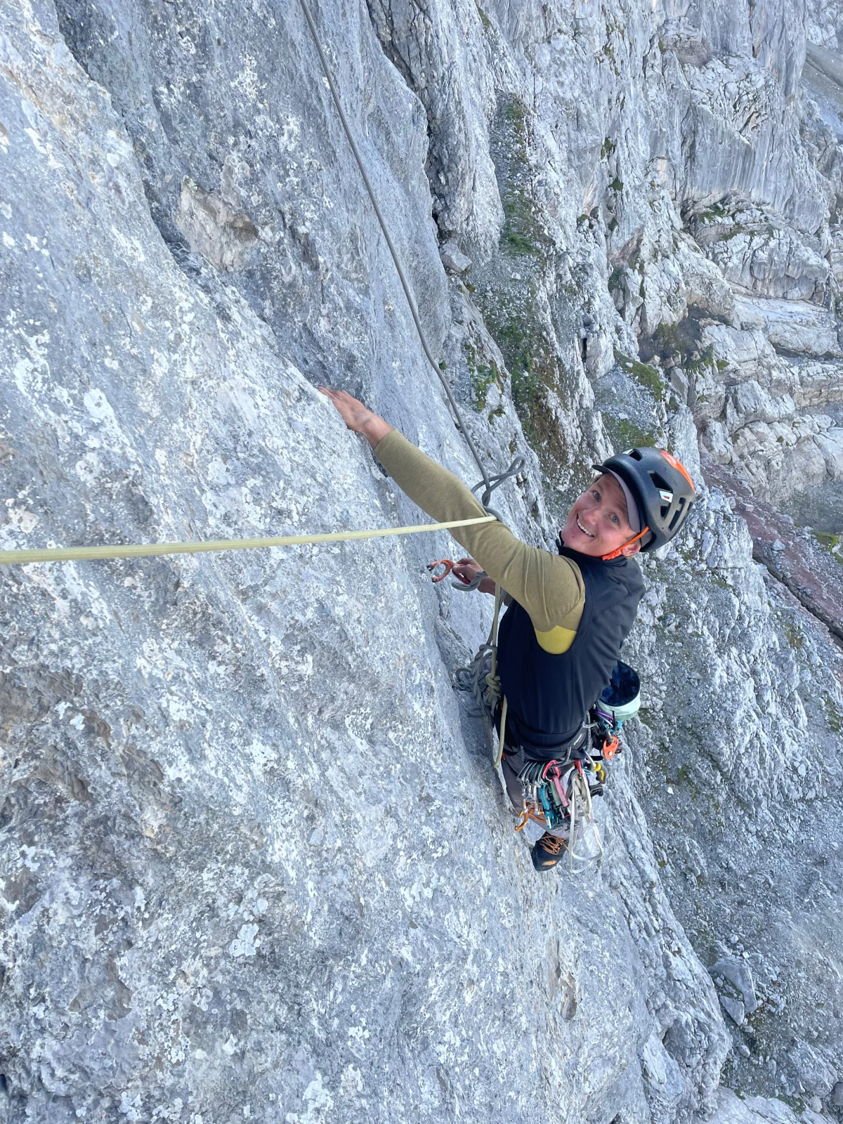 Climber wearing a helmet on a rope on a limestone wall during a leisurely alpine climb in the Lechtal valley.