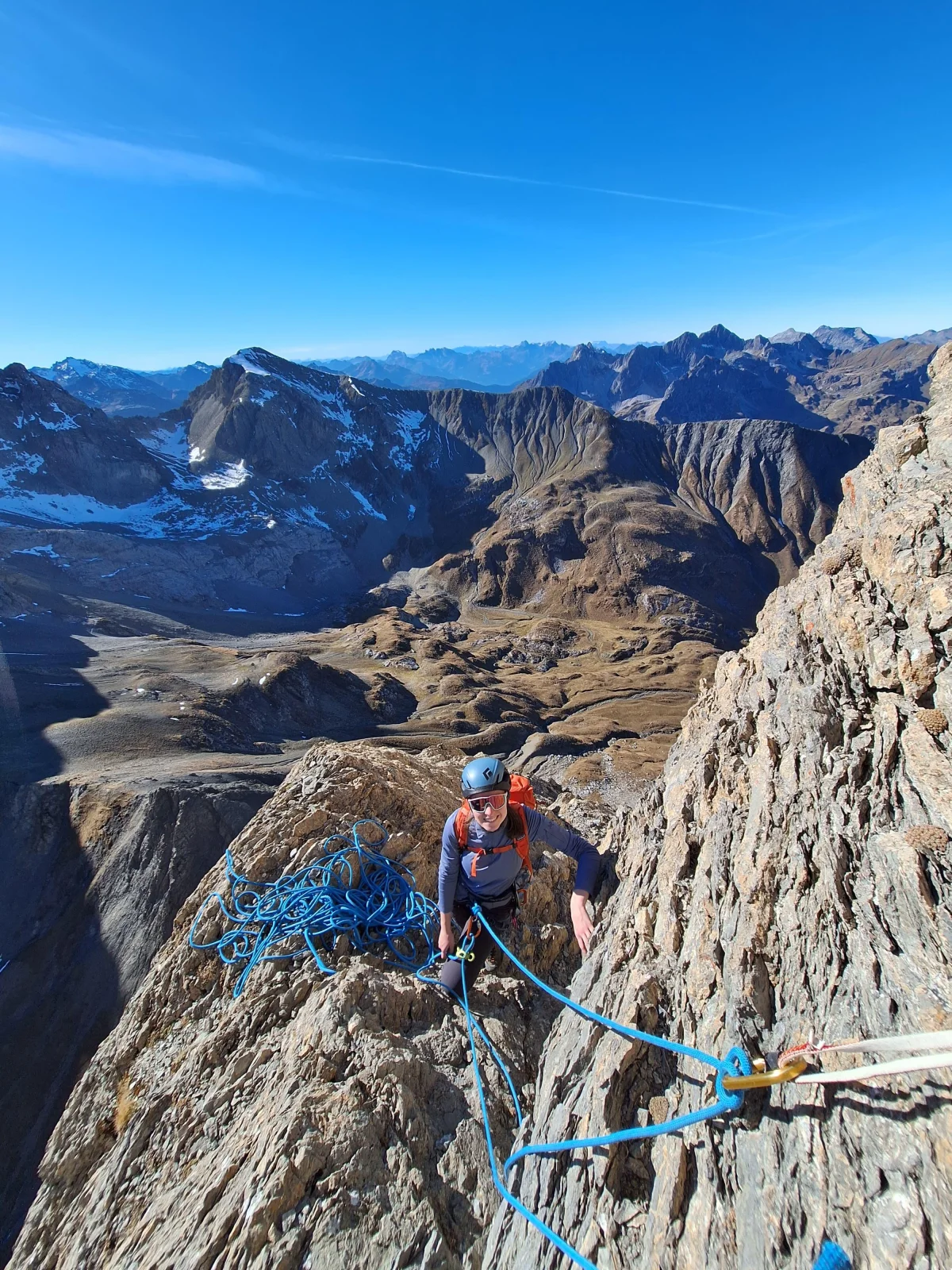 Roped climbing team at a rocky belay with views of the autumn mountain landscape.