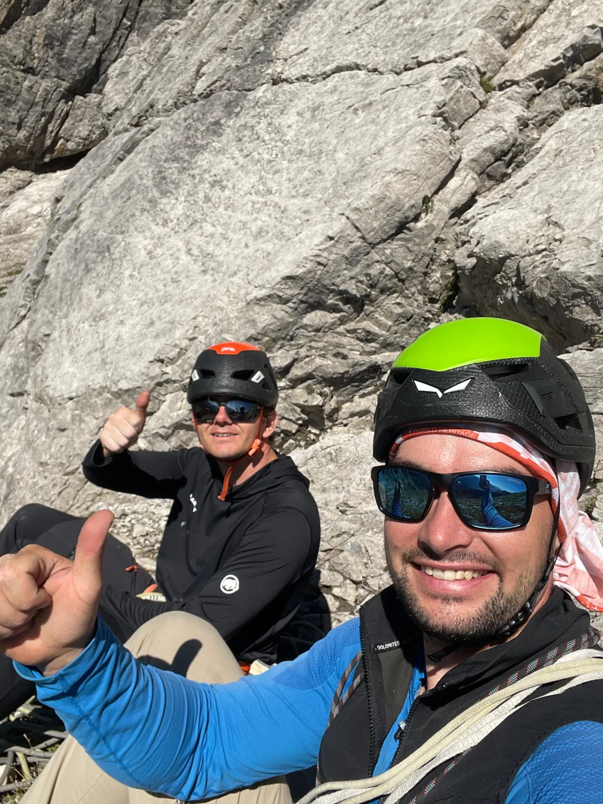 Mountain guide Ludwig Sandhacker with a climbing guest taking a break by the rock face.