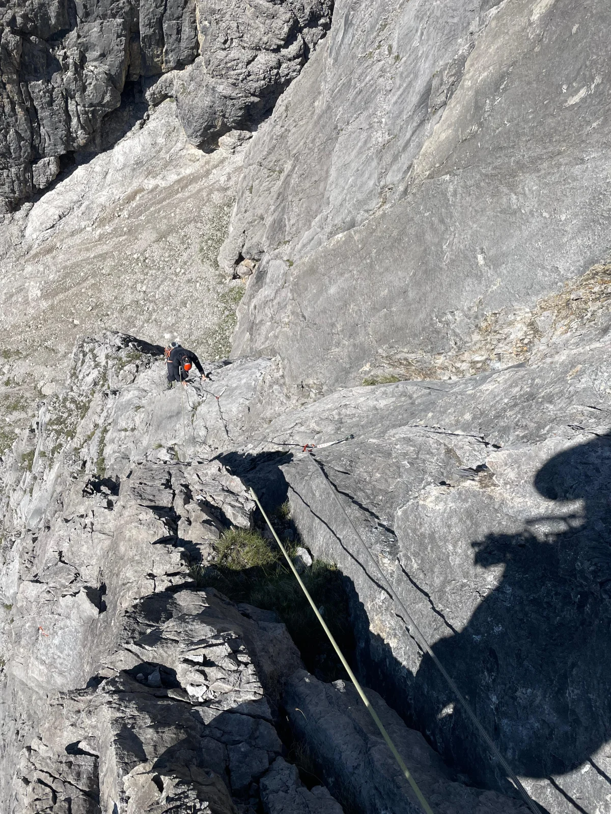 Climber following a rope up a limestone slab, photographed from above.