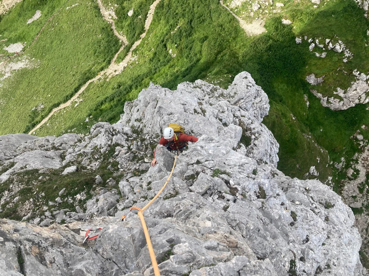 Gimpel West Ridge – Climbing Tour with Mountain Guide in the Tannheim Valley: Following roped climber wearing an orange helmet.