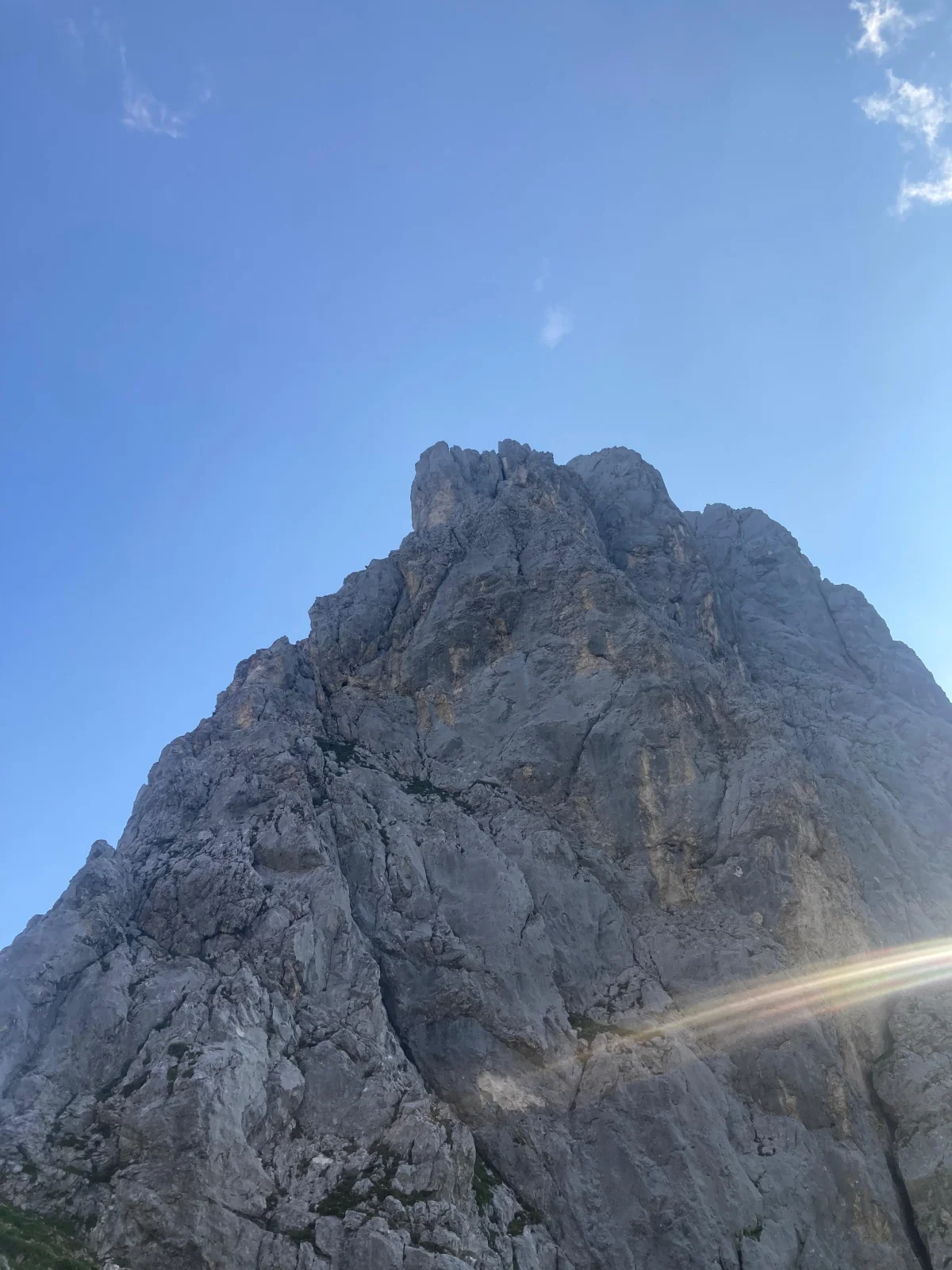 Gimpel West Ridge – Climbing Tour with Mountain Guide in the Tannheim Valley: Steep rock wall in sunlight beneath a blue sky.