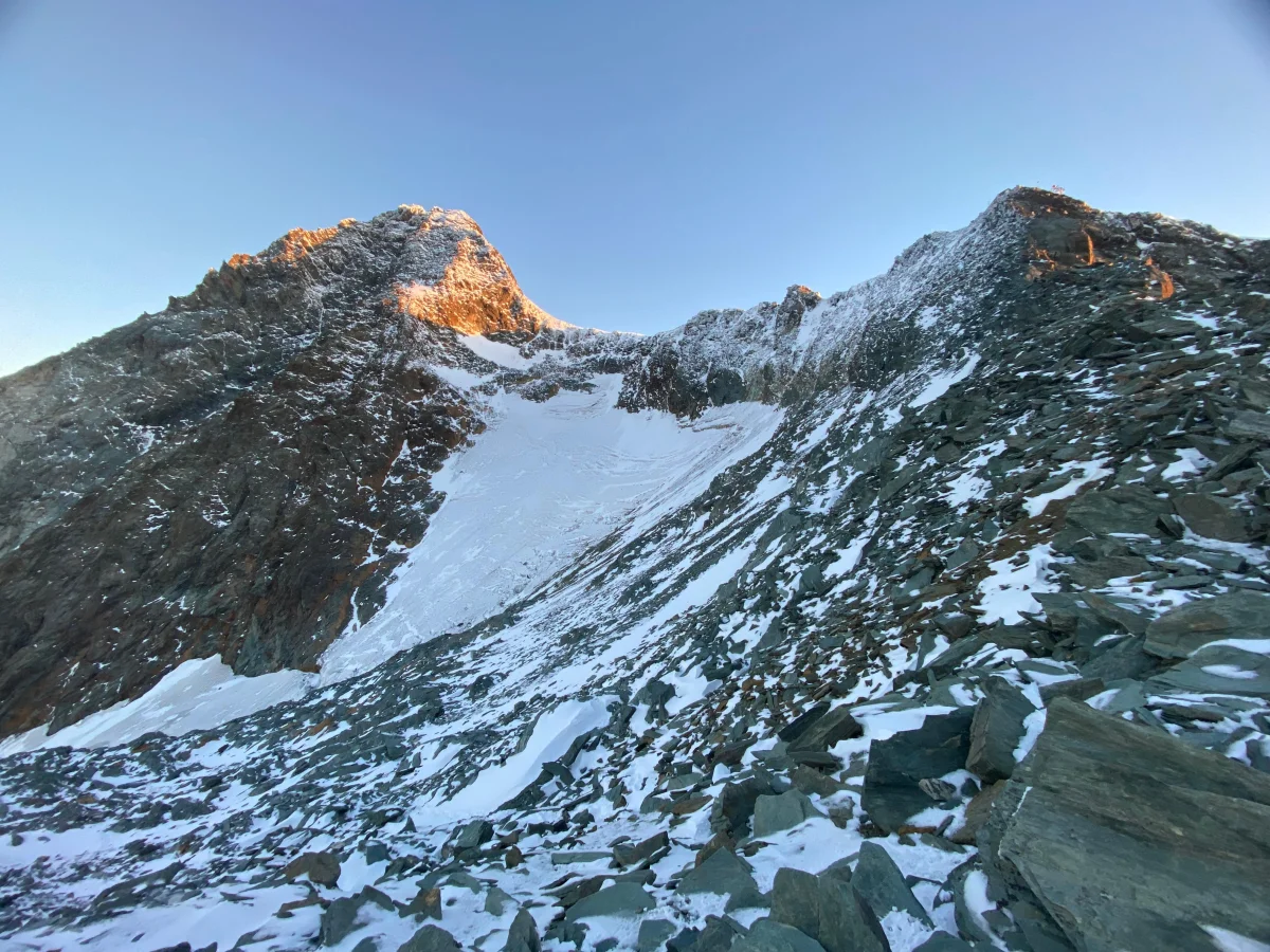 Großglockner Normal Route via Stüdlhütte: Rocky summit in morning light above a snow slope.