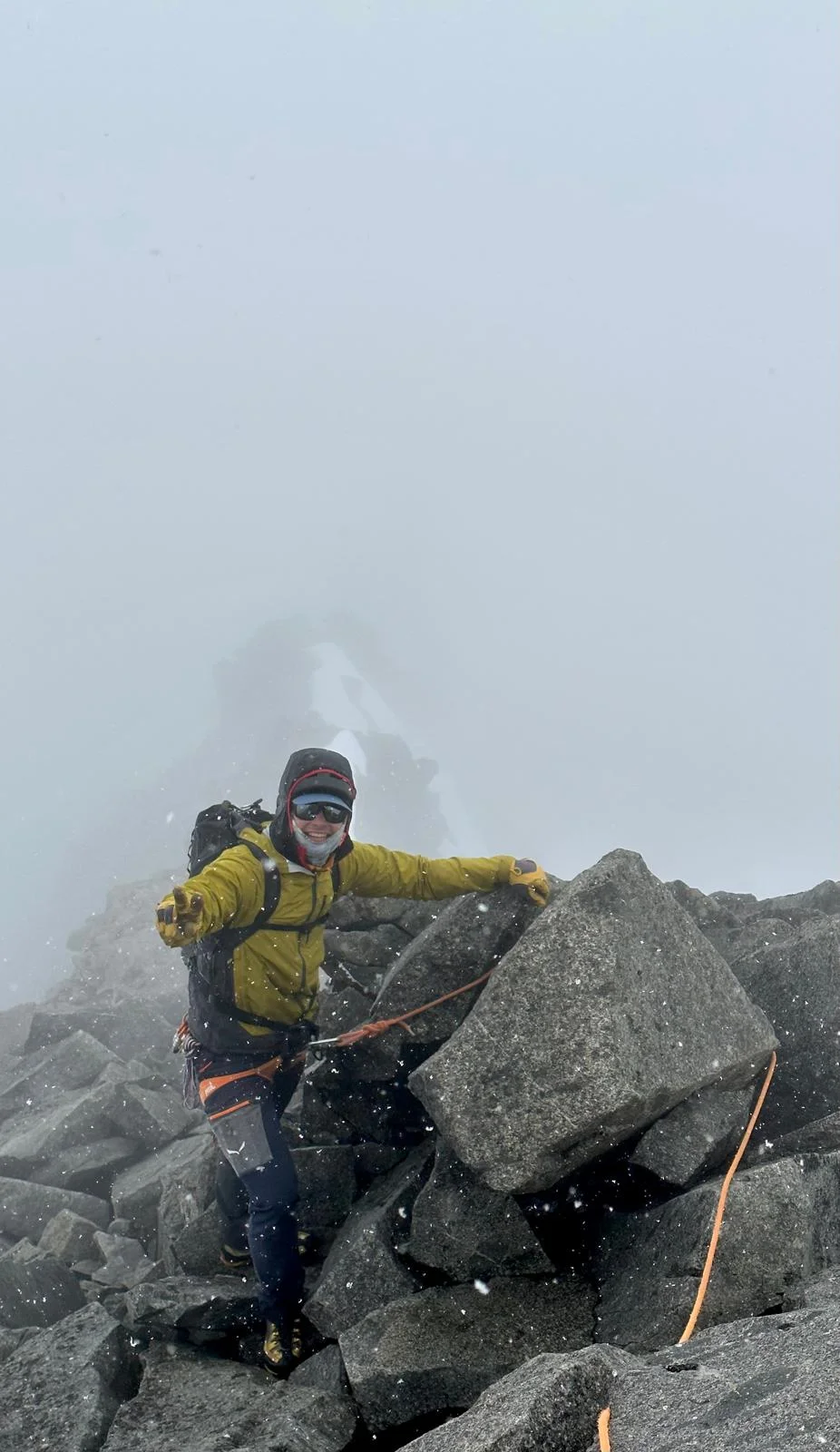 Großvenediger North Ridge with a Mountain Guide: Mountaineer in a yellow jacket among boulders in fog.