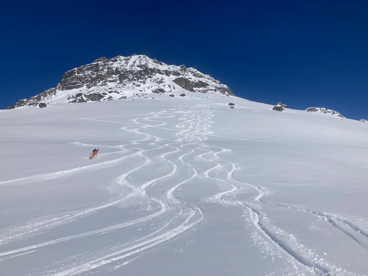 Custom Ski Traverse in the Silvretta: Curving ski tracks below a snow-covered mountain peak.