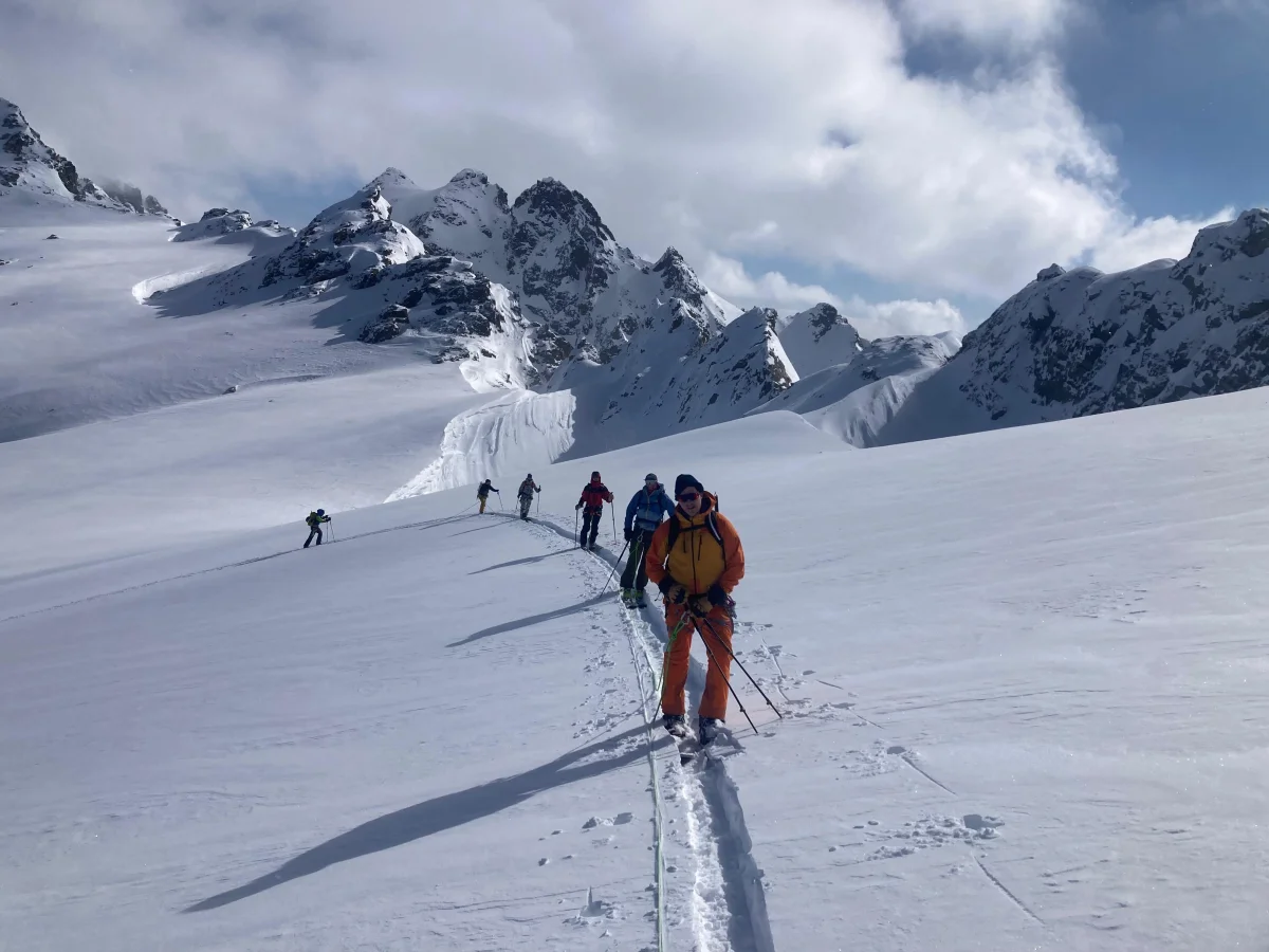 Individuelle Skidurchquerung in der Silvretta: Skitourengruppe auf einer Aufstiegsspur durch Pulverschnee.