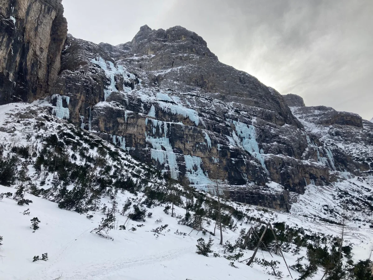 Canadian Dream – Ice Climbing in the Dolomites: Icy rock wall above snow-covered conifers.