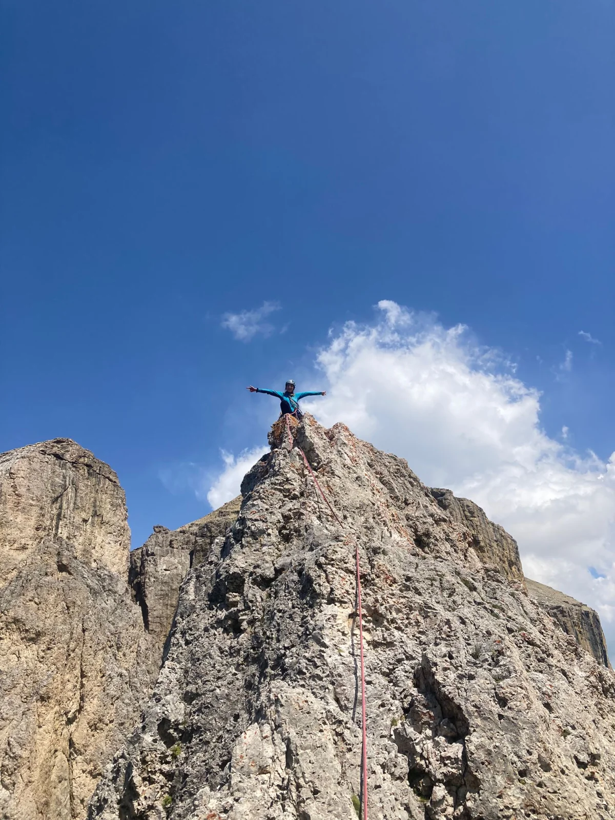 Kasnapoff – Second Sella Tower: Mountaineer with outstretched arms on a rocky summit.