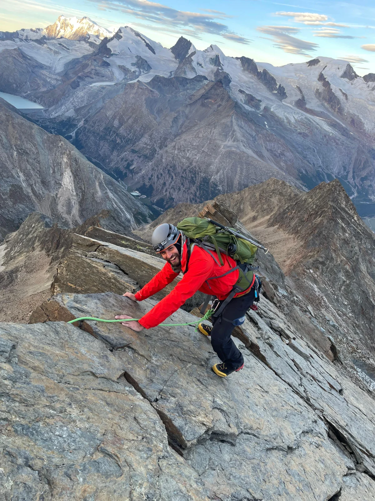 Easy 4,000-Meter Peaks in Saas-Fee: Mountaineer in a red jacket ascending rocky terrain.