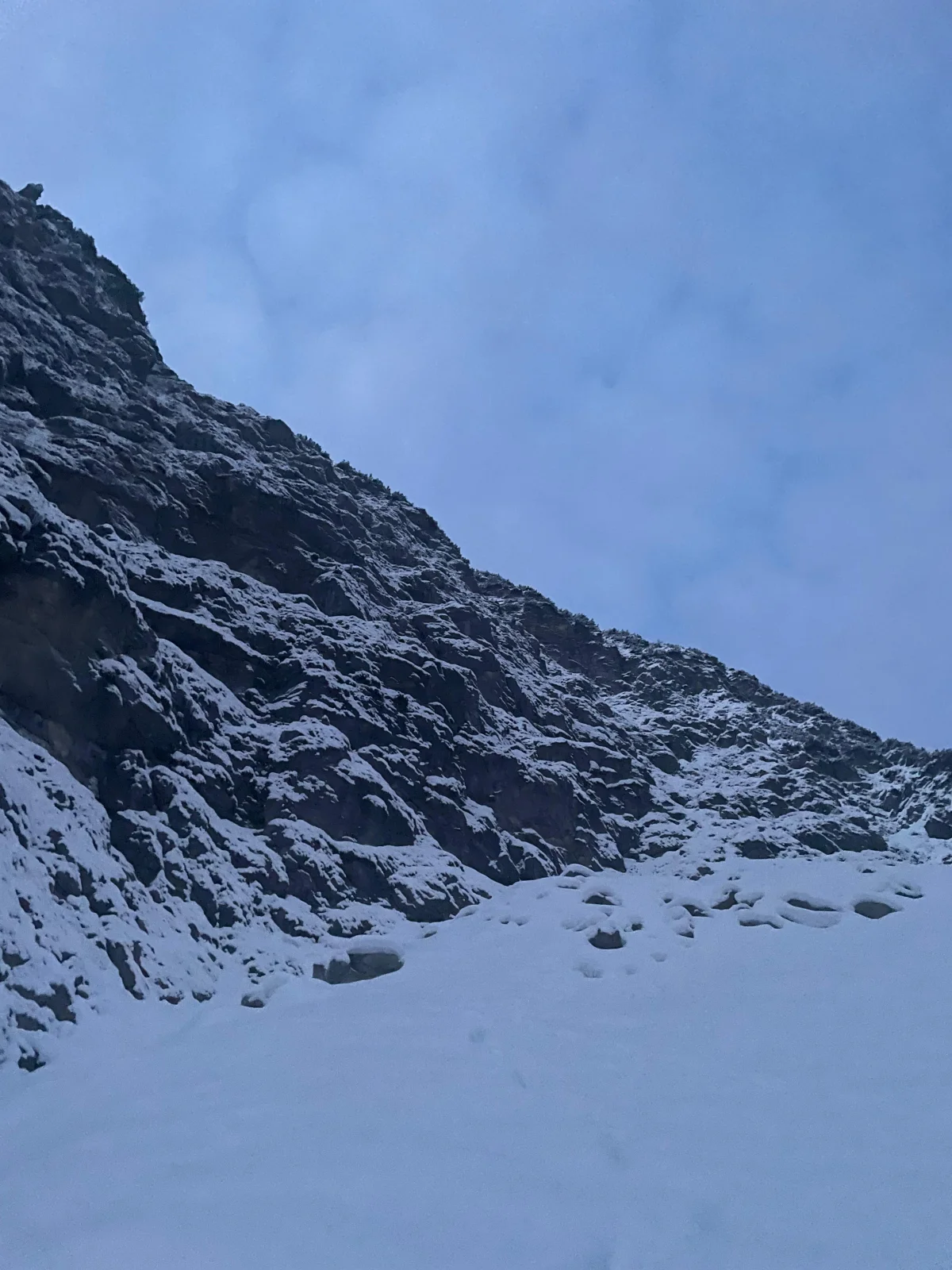 Blick vom verschneiten Wandfuß hinauf in die felsige Rubihorn-Nordwand.