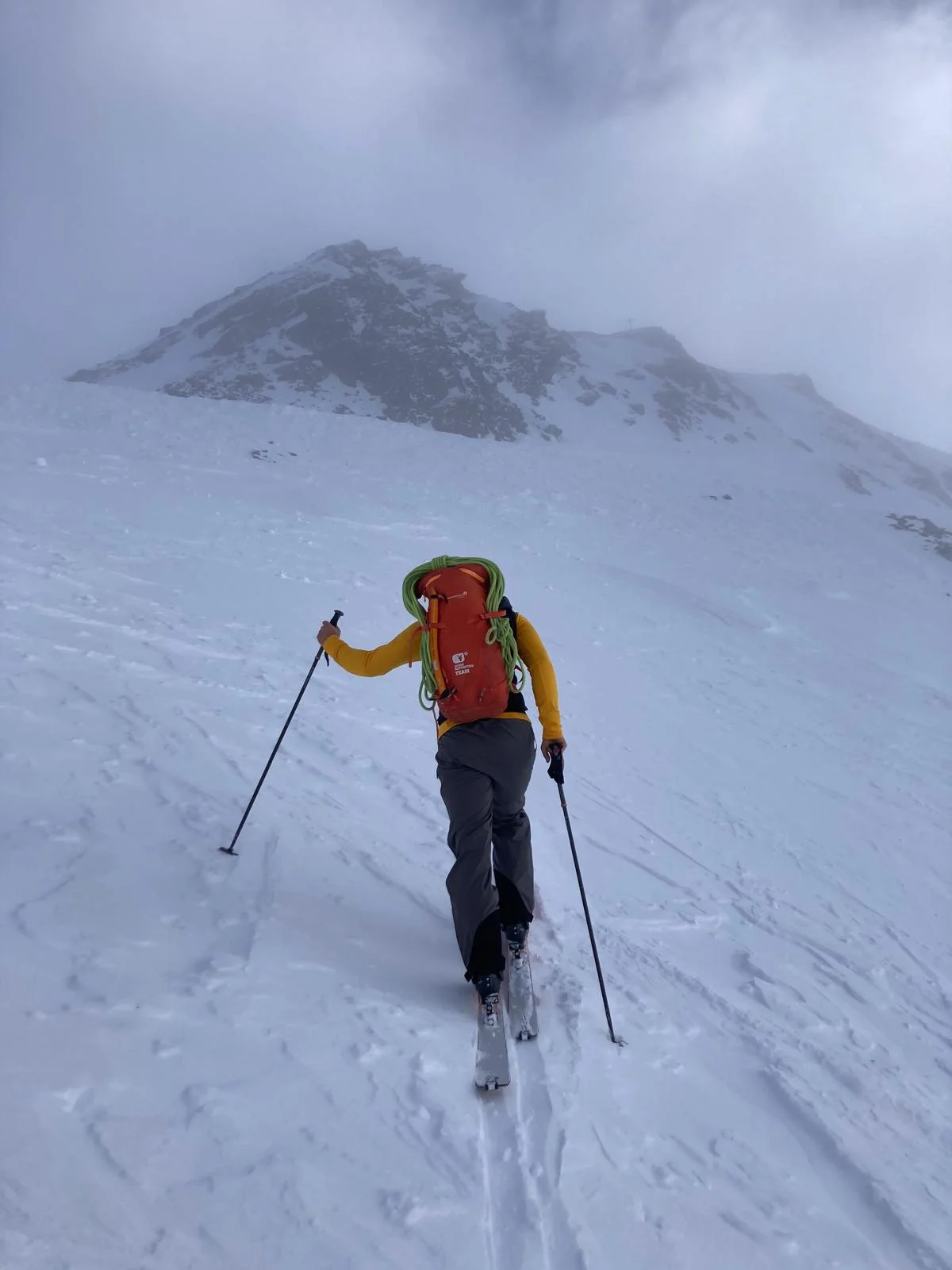 Ski Mountaineering on the Franz Senn Hut: Ski tourer with an orange backpack in snowfall.