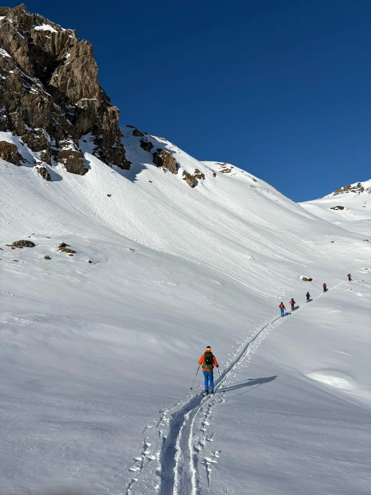 Ski Mountaineering on the Franz Senn Hut: Ski tourer following a trail between a rock wall and snow slope.