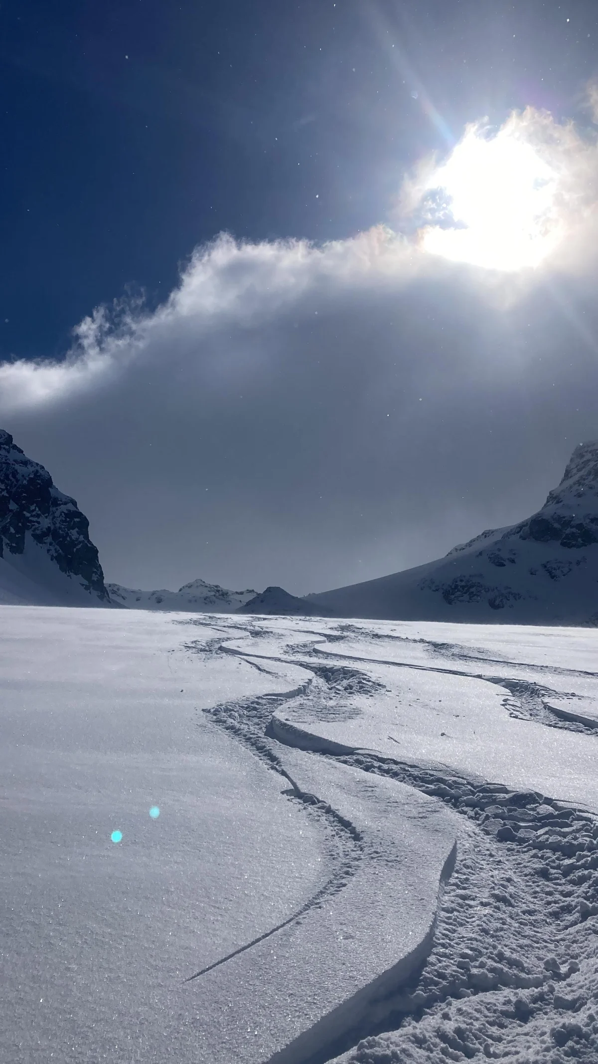 Ski Touring in the Lechtal with a Ski Guide: Ski tracks backlit by the sun beneath clouds.