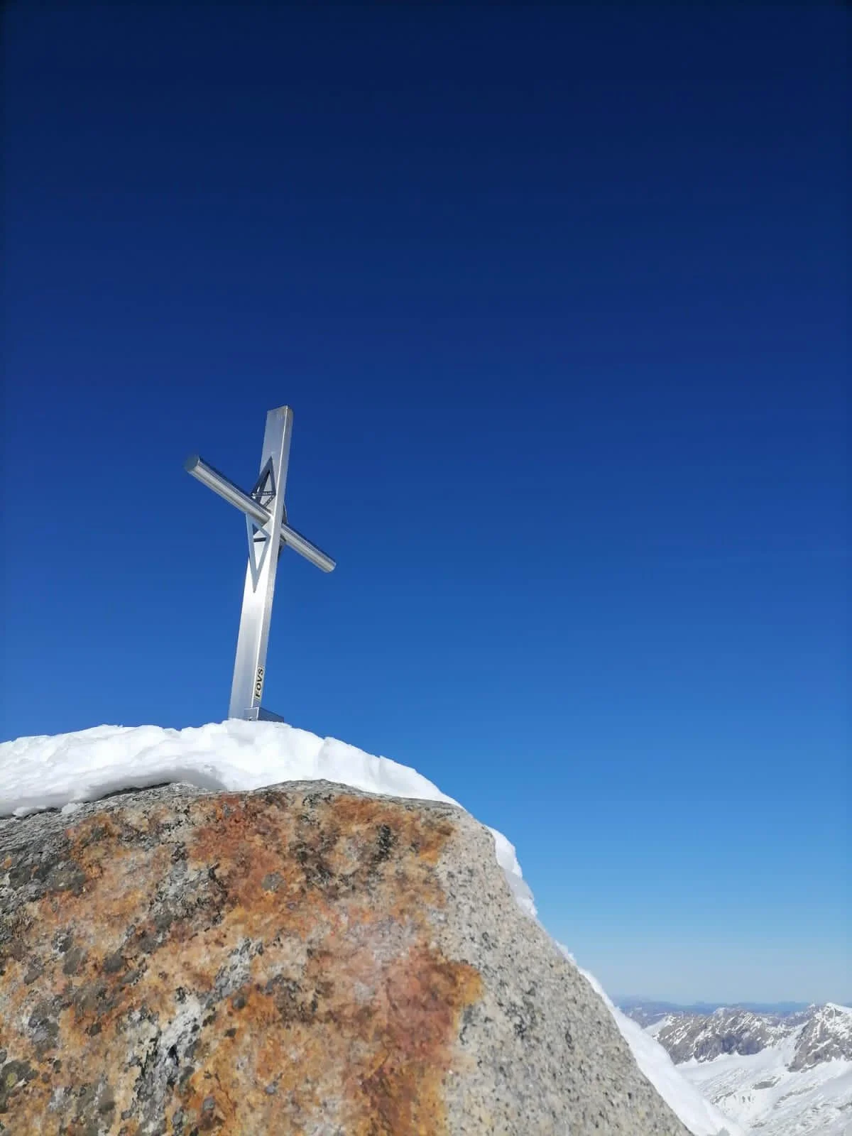 Turnerkamp South Ridge: Summit cross on a rocky peak beneath a blue sky.