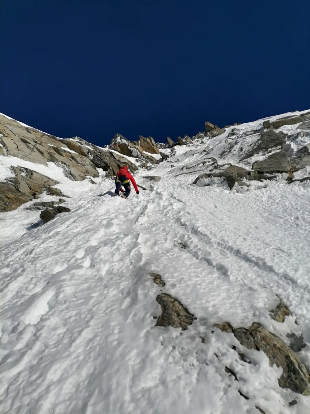 Turnerkamp South Ridge: Following mountaineer on snow-covered rock slabs.