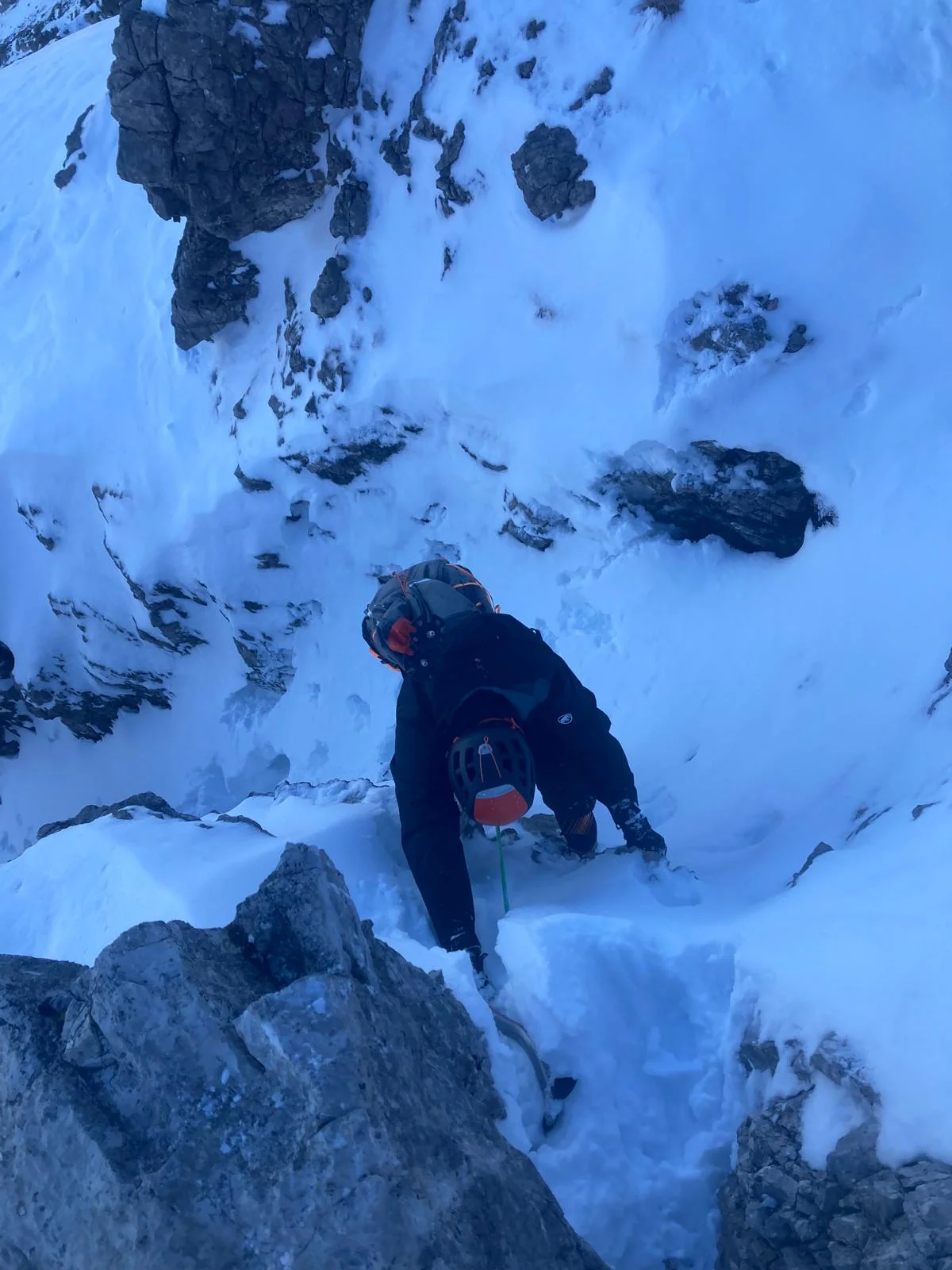Winter Mountaineering on Thaneller: Mountaineer climbing over snow-covered rock.